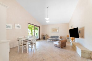 A spacious living area with a dining table, chairs, a sofa, a TV, and artwork on the walls. - Masseria Saracino Pool And Garden, Martano, Italy (Martano)