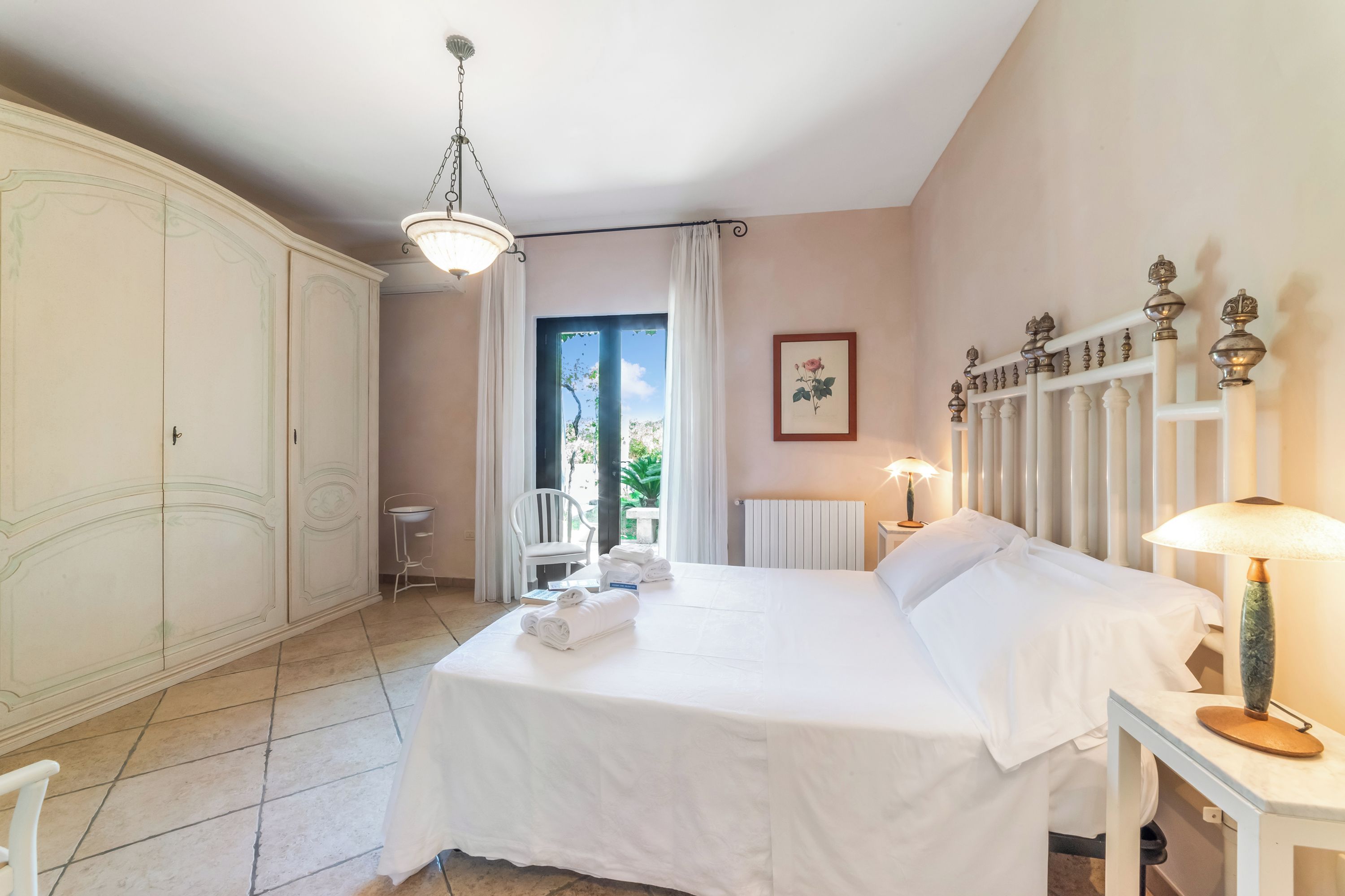 Une chambre d’hôtel avec un lit, une chaise, une table, un radiateur et une fenêtre avec des rideaux.