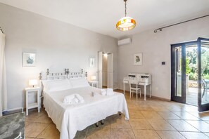 Ein Hotelzimmer mit Bett, Nachttischen, einem Schreibtisch und Blick ins Freie.