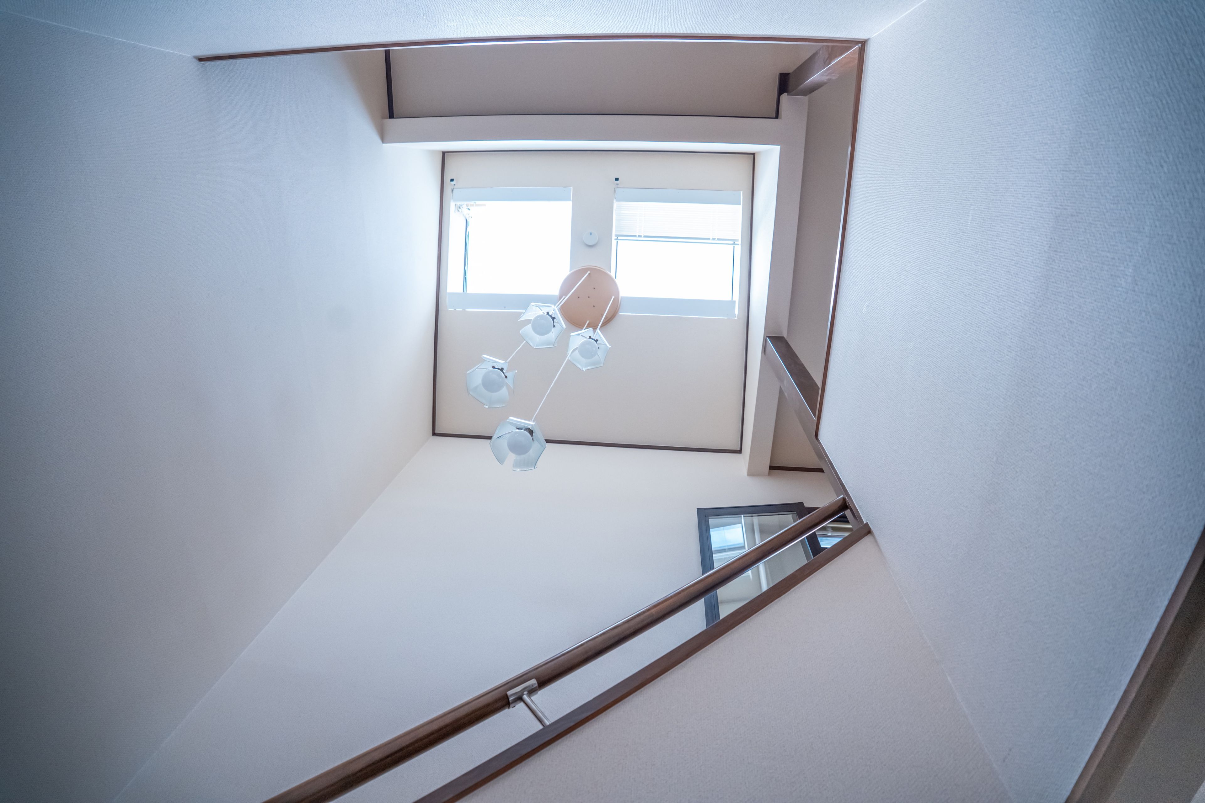 A corner of a room with a window, a wooden handrail, and a ceiling light fixture.