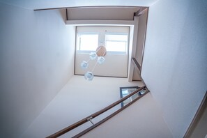 A corner of a room with a window, a wooden handrail, and a ceiling light fixture.