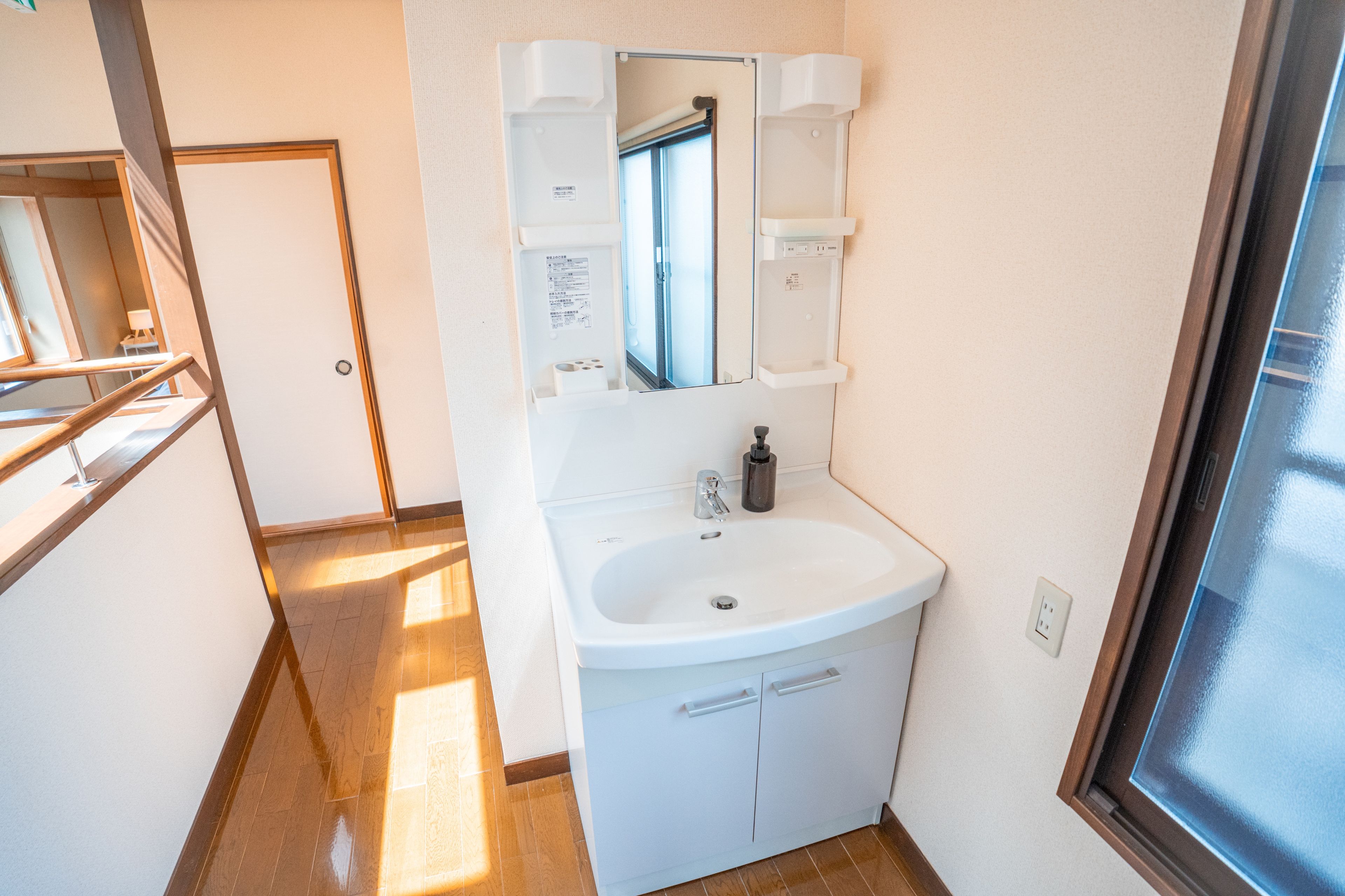 A small, clean bathroom with a white sink, a mirror, and a window.