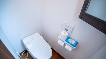 Ein kleines, modernes Badezimmer mit Toilette, Toilettenpapierhalter und Bidet.