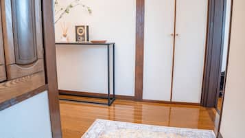 Et traditionelt japansk interiør med tatamimåtter, en shoji skærmdør og et lille bord med et ur og røgelse.
