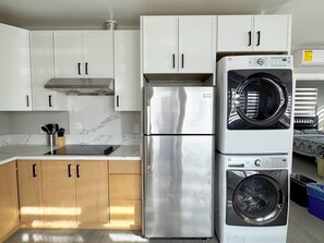 A kitchen with white cabinets, a stainless steel refrigerator, a built-in oven, and a washing machine. - 5706- Cute 2B1B Private Unit near FWY 580/24 & UCB (Oakland)