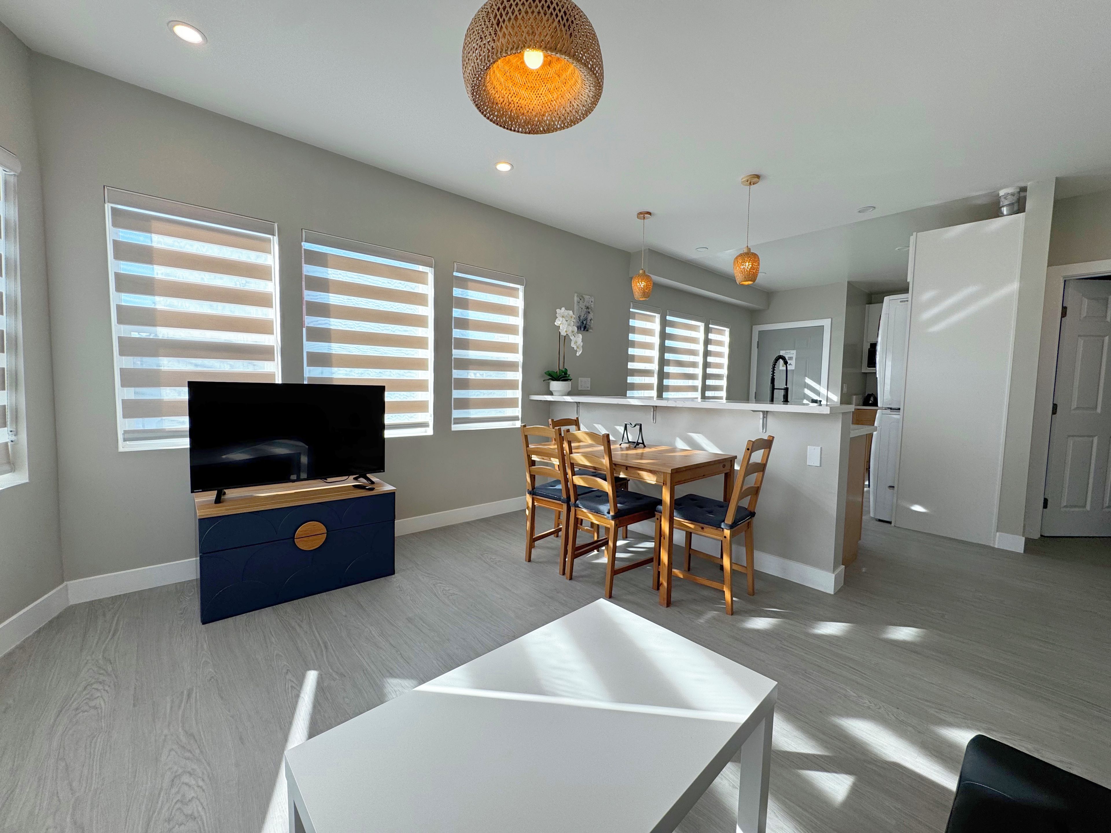 A modern living room with a flat-screen TV, dining table, and chairs.