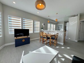 A modern living room with a flat-screen TV, dining table, and chairs. - 5706- Cute 2B1B Private Unit near FWY 580/24 & UCB (Oakland)