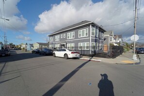 A residential street with a two-story house, parked cars, and a clear sky. - 5706- Cute 2B1B Private Unit near FWY 580/24 & UCB (Oakland)