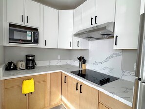 A modern kitchen with white cabinets, a microwave, a stove, and a coffee maker. - 5706- Cute 2B1B Private Unit near FWY 580/24 & UCB (Oakland)