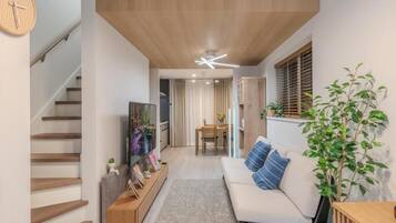 A modern living room with a staircase, a sofa, a coffee table, and a TV.