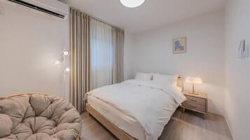 A bedroom with a bed, bedside table, lamp, and a chair.