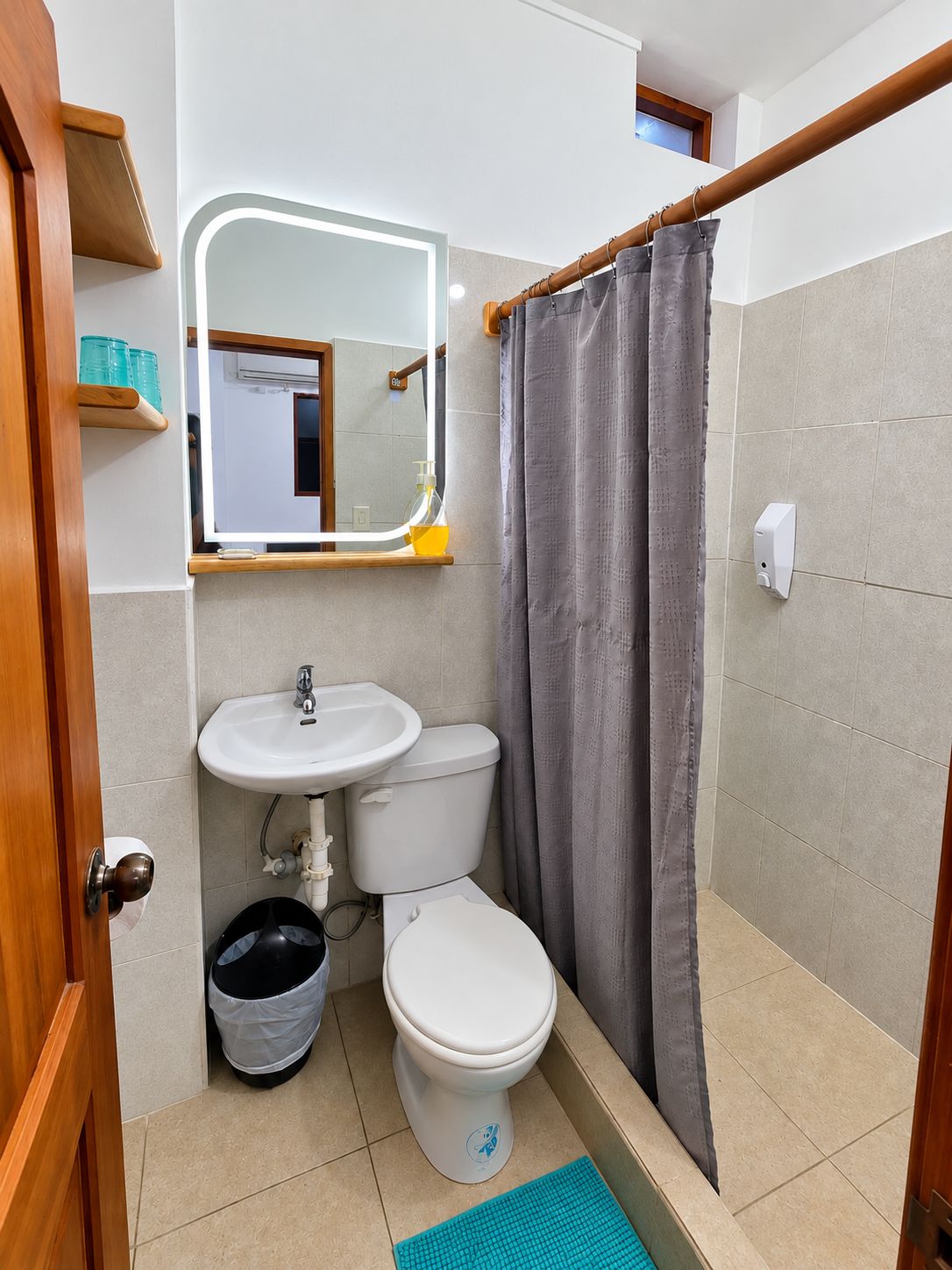 Une petite salle de bain avec un lavabo blanc, des toilettes et un espace douche séparé par un rideau.