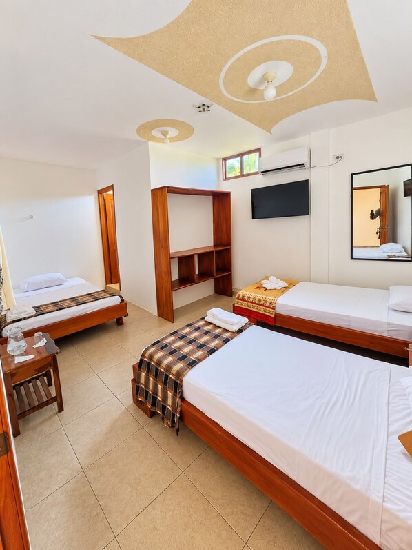 Una habitación de hotel con dos camas, un armario de madera, un televisor y un ventilador de techo.