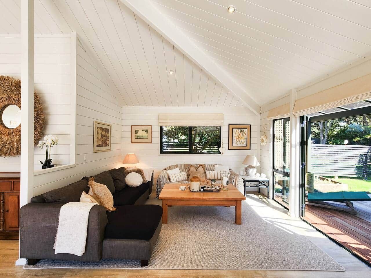 A spacious living room with a high ceiling, a wooden coffee table, and a sofa set.