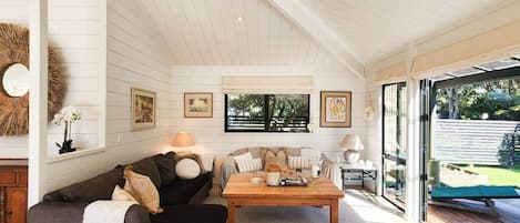 A spacious living room with a high ceiling, a wooden coffee table, and a sofa set.
