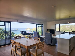 Cuina moderna amb una illa gran, zona de menjador amb caires i vista al mar.