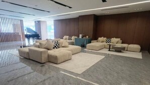 Amplia sala de estar con un sofá modular grande, un sofá más pequeño y una mesa de centro. El piso es de mármol y las paredes tienen paneles de madera.