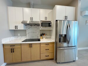 A kitchen with white cabinets, a stainless steel refrigerator, a microwave, and a marble countertop. - 5710- Safe 2B1B Private Unit near FWY 580/24 & UCB (Oakland)