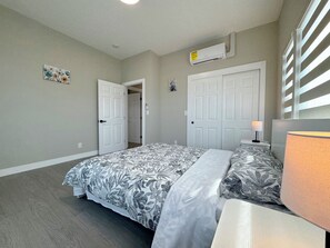 A bedroom with a bed, a nightstand, a lamp, and an air conditioning unit. - 5710- Safe 2B1B Private Unit near FWY 580/24 & UCB (Oakland)