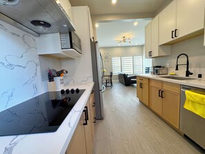 A modern kitchen with a black stovetop, white cabinets, and a yellow towel hanging on the dishwasher. - 5710- Safe 2B1B Private Unit near FWY 580/24 & UCB (Oakland)