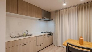 Een moderne keuken met houten kastjes, een roestvrijstalen spoelbak en een eethoek met een tafel en stoelen.