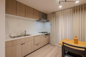 Una cocina moderna con armarios de madera, un lavamanos de acero inoxidable y un comedor con mesa y sillas.