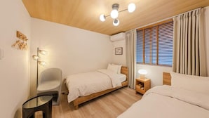 Een slaapkamer met twee bedden, een nachtkastje, een stoel, een vloerlamp en een plafondlamp.