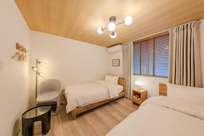 Un dormitorio con dos camas, una mesita de noche, una silla, una lámpara de pie y una lámpara en el techo.
