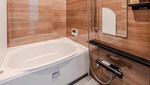 Een moderne badkamer met een badkuip, douche en een wastafel met spiegel.