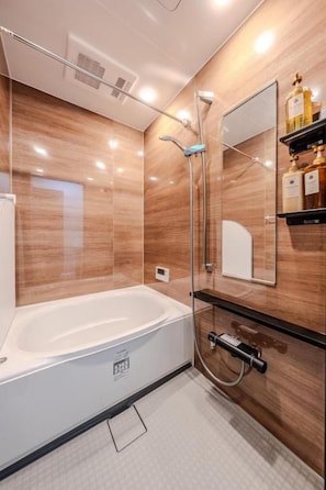 Un baño moderno con bañera, ducha y tocador con espejo.