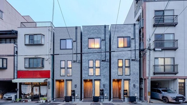 Een rij moderne gebouwen met een rij deuren en ramen, een parkeerplaats en een voertuig.