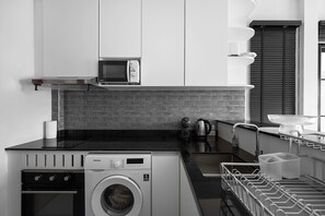 Eine moderne Küche mit integriertem Waschtrockner, einer Mikrowelle und einer Kaffeemaschine.