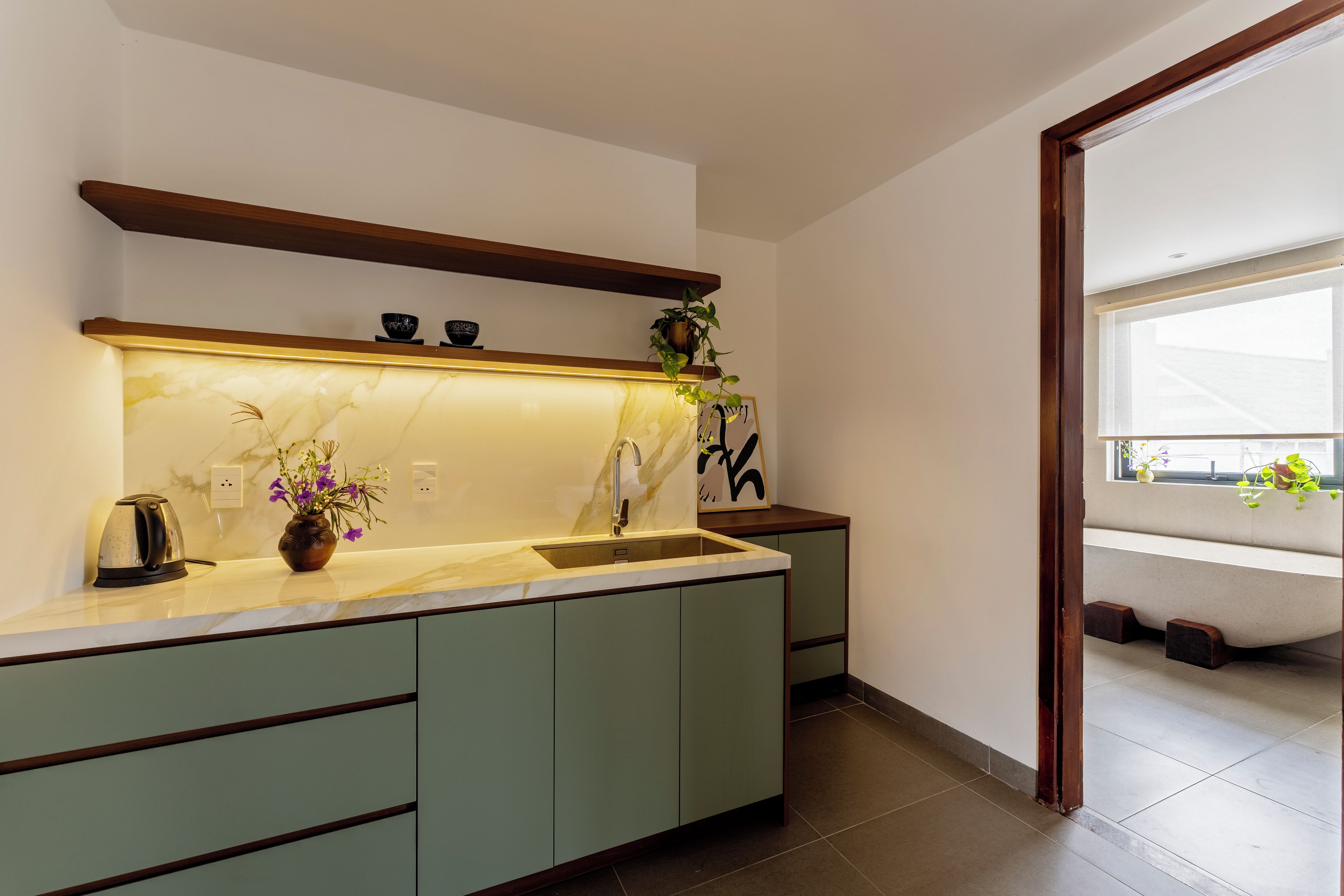 Una cocina moderna con encimera de mármol, pileta integrada y estante de madera.