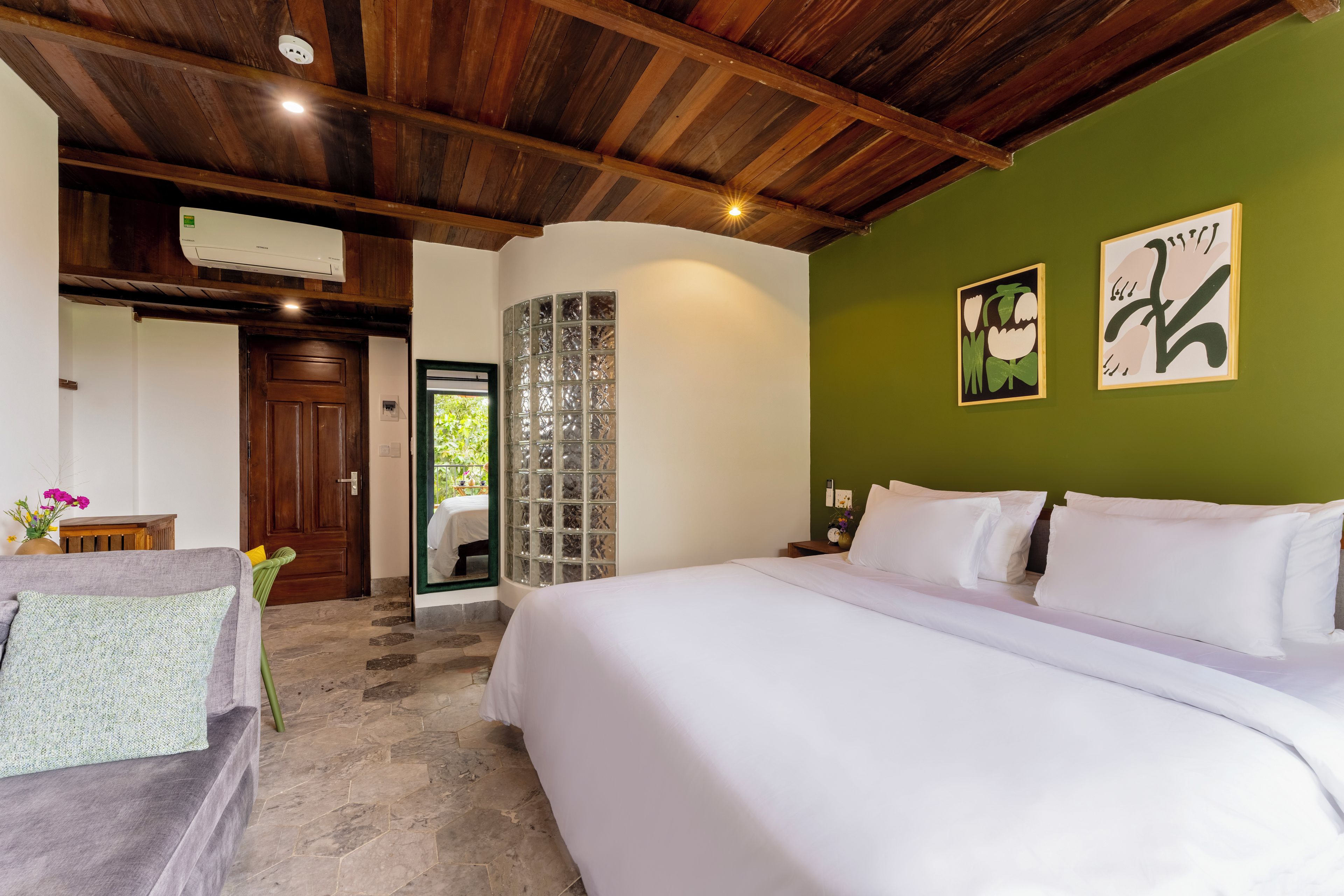 Un dormitorio con cama, mesita de noche, aire acondicionado instalado en la pared y una puerta que da a otra habitación.