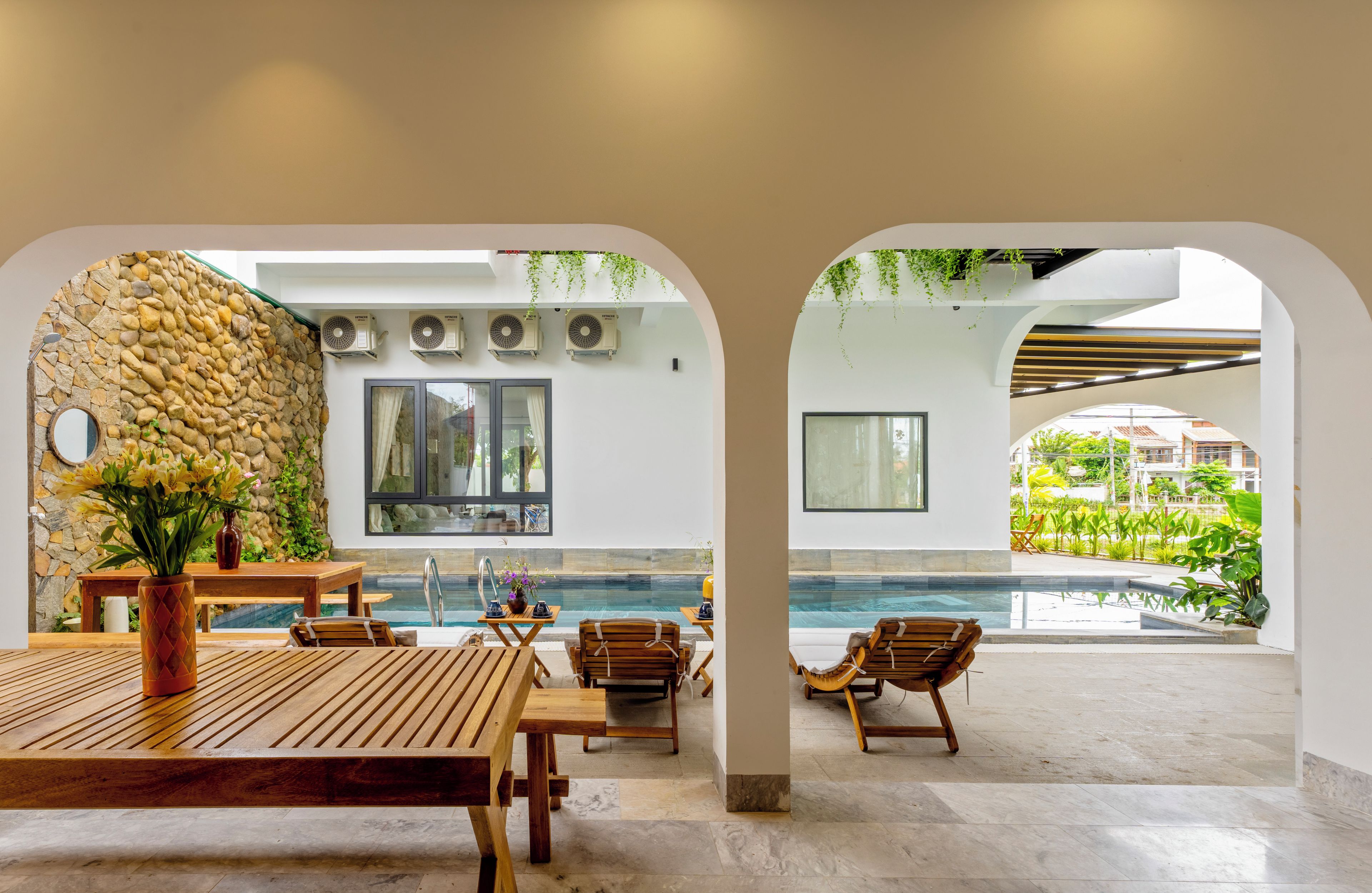 Zona junto a la piscina con pared de piedra, asientos y vistas a una piscina.