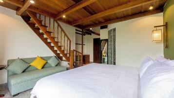 Un dormitorio con una cama grande, una escalera de madera, un sofá verde con cojines amarillos y una pared verde.