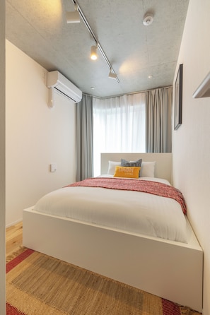 Ein modernes Hotelzimmer mit einem großen Bett, einem Deckenventilator, einer Klimaanlage und einem Fenster mit Vorhängen.
