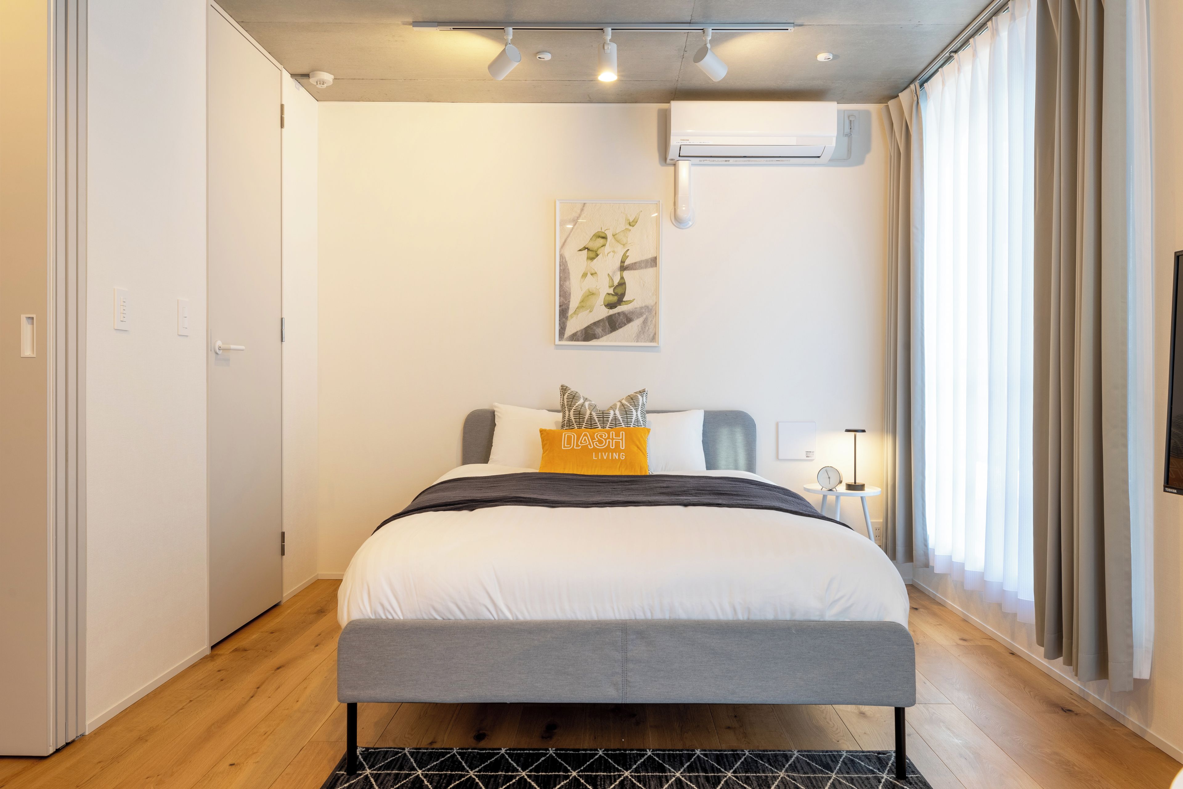 Un dormitorio moderno con cama, mesita de noche y aire acondicionado de pared.