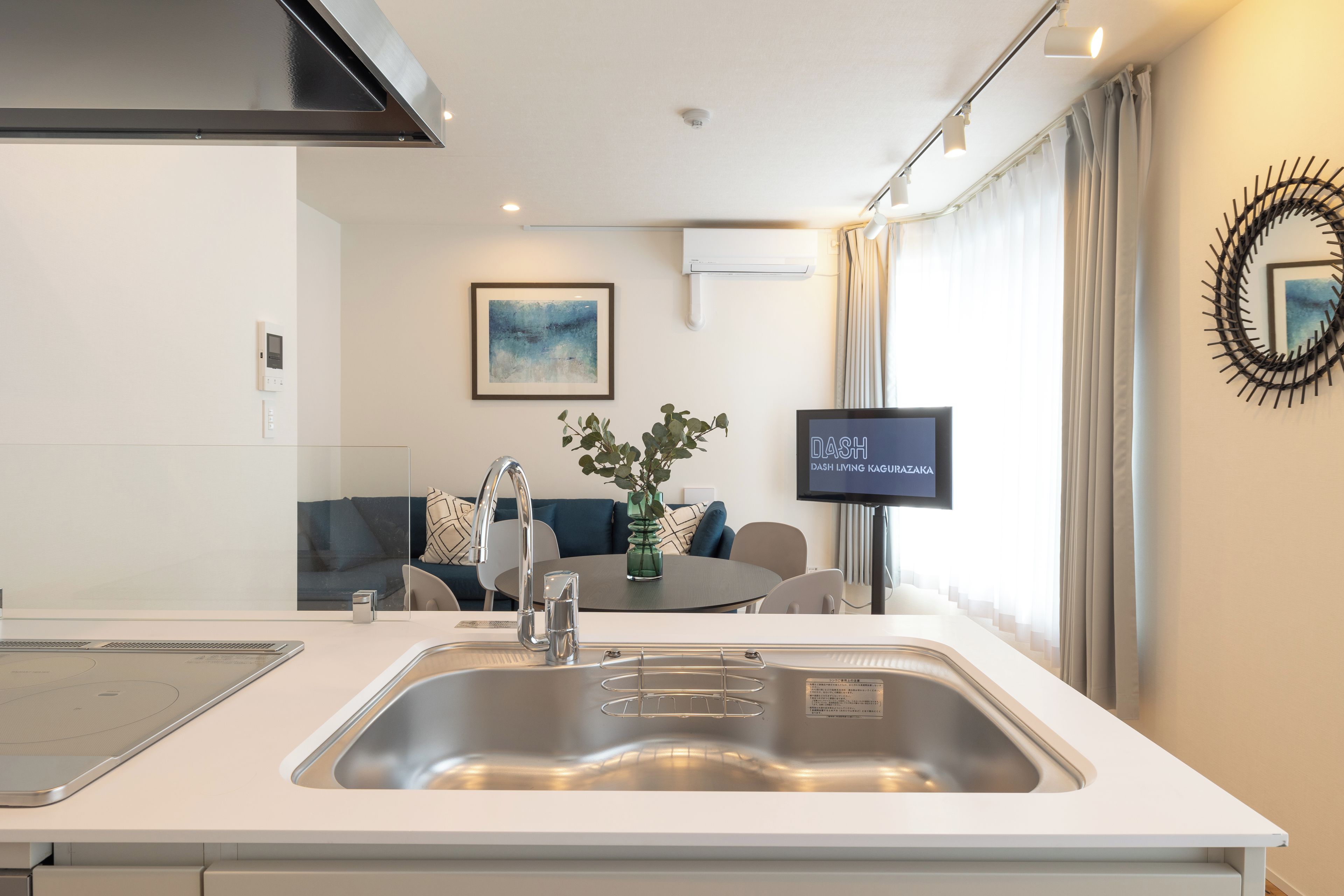A modern kitchen with a stainless steel sink, a built-in stove, and a dining area with a table and chairs.