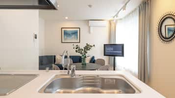 A modern kitchen with a stainless steel sink, a built-in stove, and a dining area with a table and chairs.