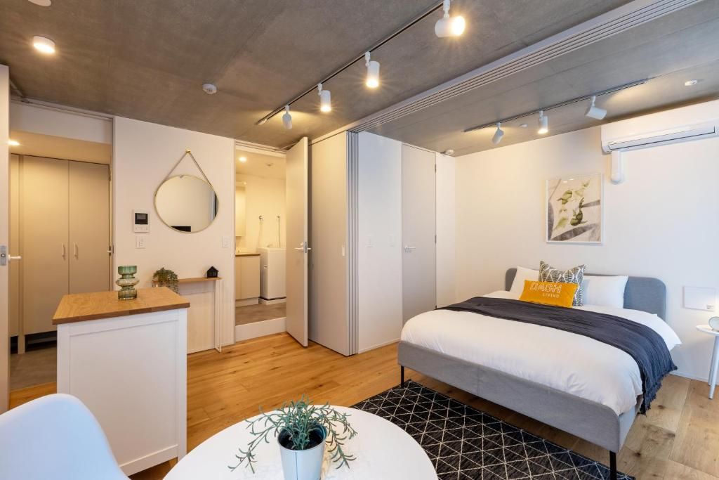 Quarto moderno com cama, mesa de cabeceira e pequeno espaço de trabalho.