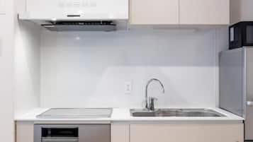 Uma cozinha moderna com armários brancos, uma pia de aço inoxidável e um forno embutido.