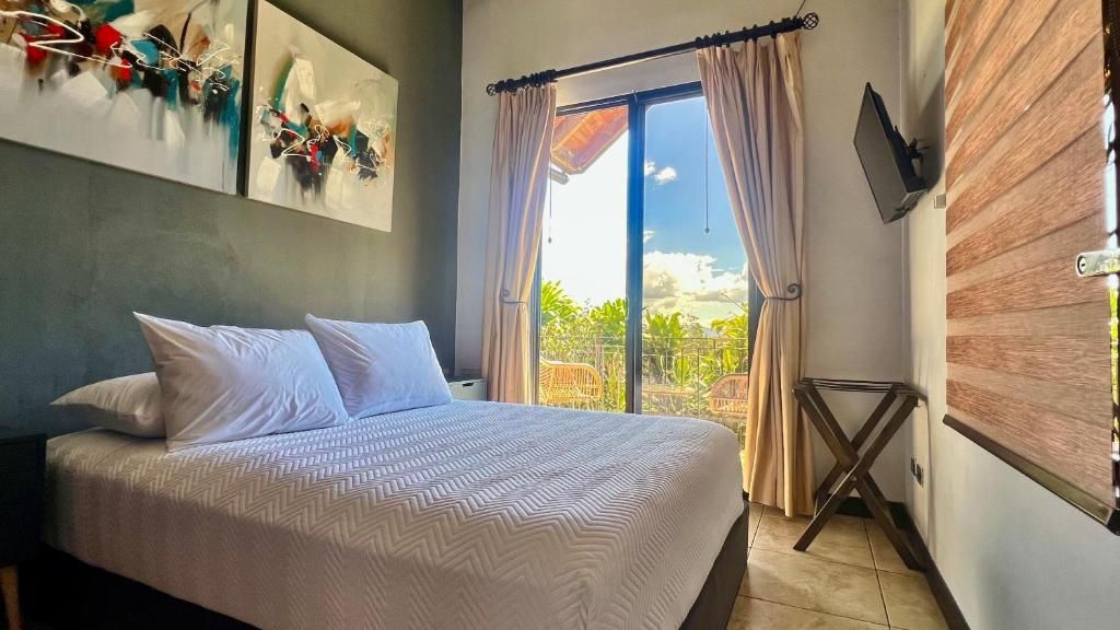 Un dormitorio con cama, televisor montado en la pared y vistas al exterior.