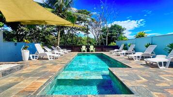 Una piscina con sillas de descanso y una zona con sombra.