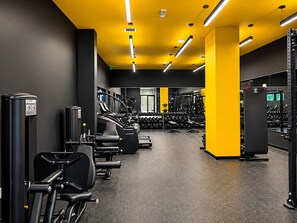 Ein Fitnessraum mit Trainingsgeräten, Gewichtsständern und Laufband.