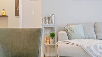 A living room with a grey sofa, a small white side table with decorative items, and a grey armchair.