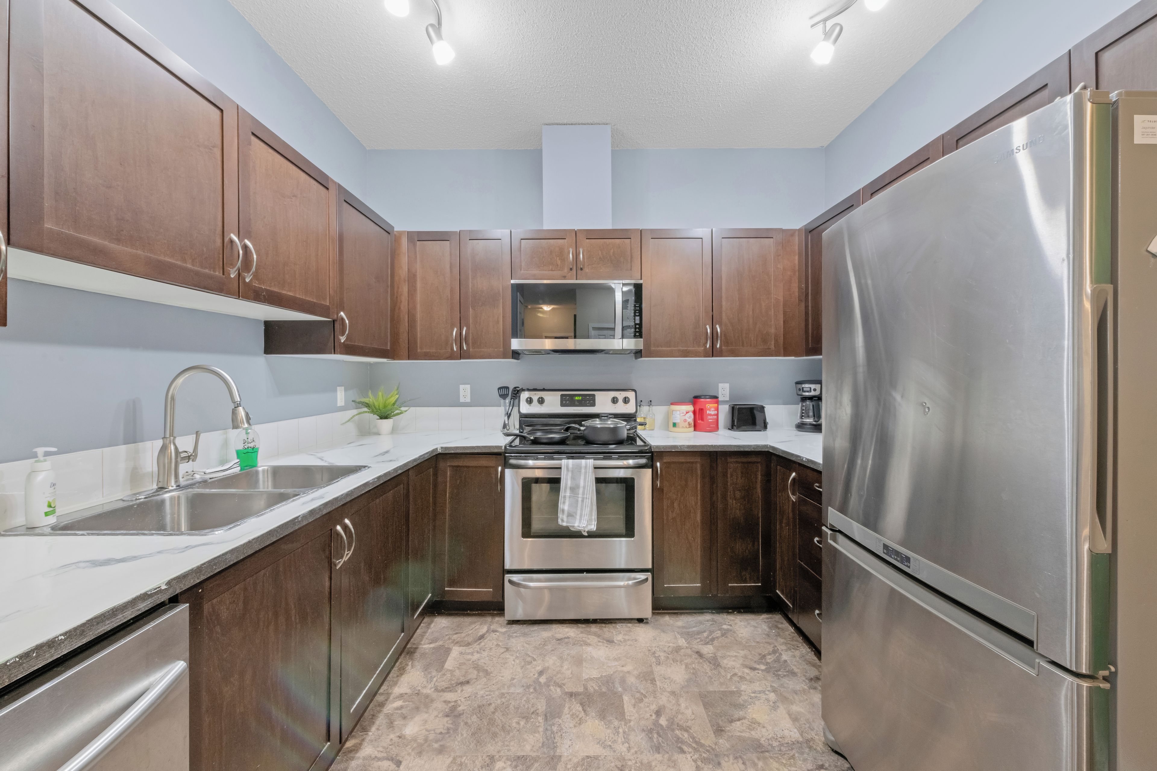 Una cocina con armarios de madera, electrodomésticos de acero inoxidable, un microondas y un refrigerador.