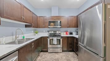 A kitchen with wooden cabinets, stainless steel appliances, a microwave, and a refrigerator.