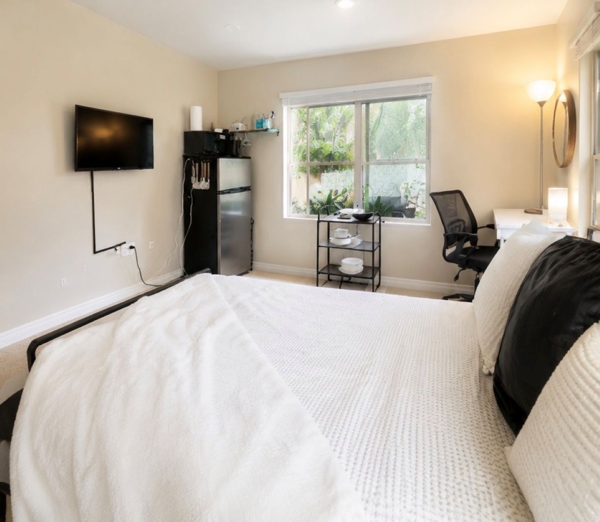 Une chambre à coucher avec un lit, une télévision, un bureau et une fenêtre.