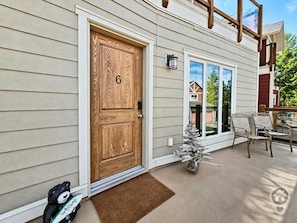 A house with a wooden door marked with the number 6, a front porch with chairs, and a mailbox. - Mountain View Home / Pet Friendly / AC (Invermere)